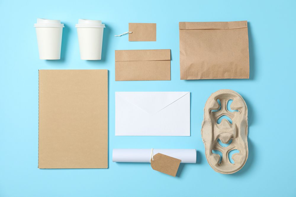 Flat lay. Paper cups and office supplies on blue background, copy space