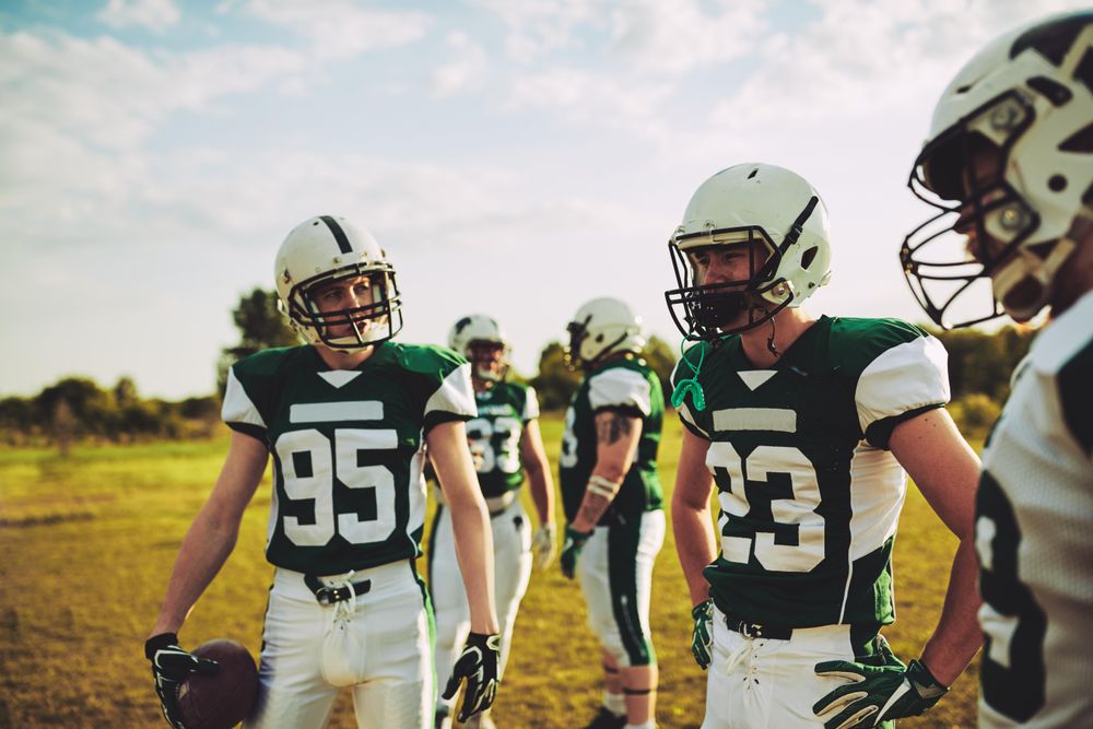 Men strategizing together during football practice