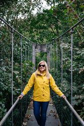 Cheerful female tourist standing on hanging bridge in summer