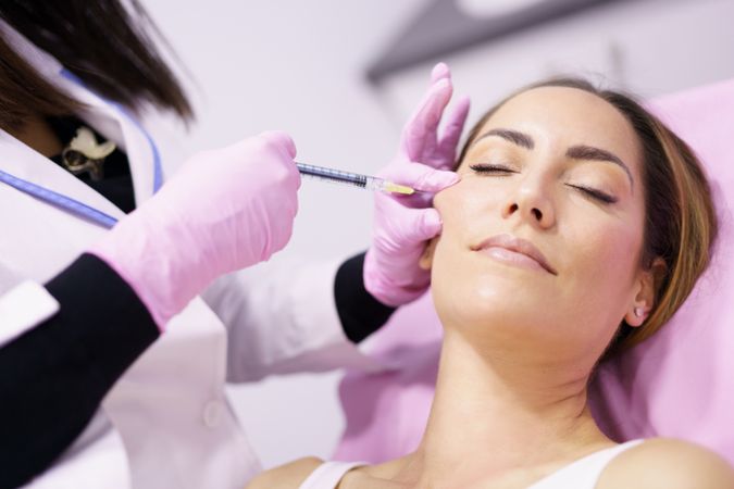 Woman having fillers injected into the side of her face