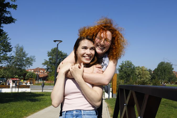 Red haired woman hugging her friend from behind