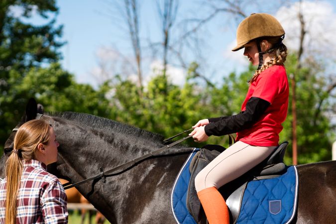 Young rider holding reins focused on equestrian training outdoors.