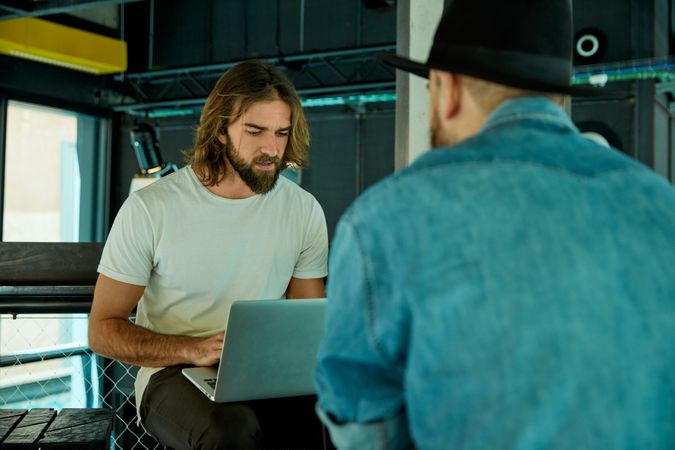 Men sitting and working on laptops indoors