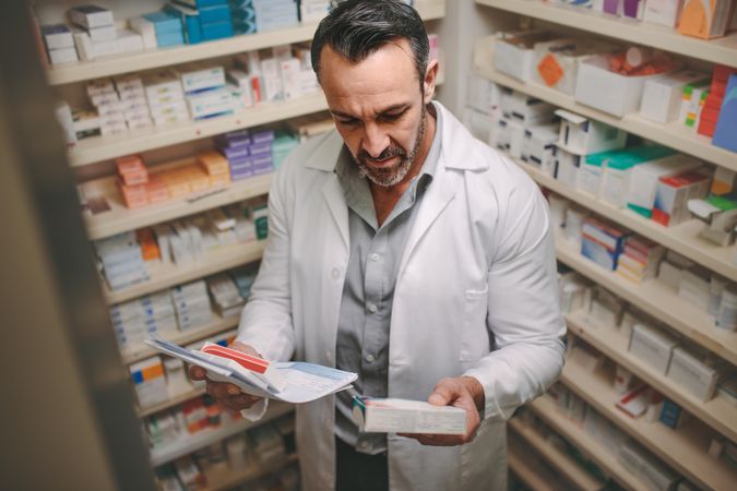 Male pharmacist searching for medicine in pharmacy