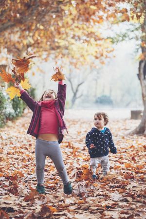 kids playing with leaves in autumn park