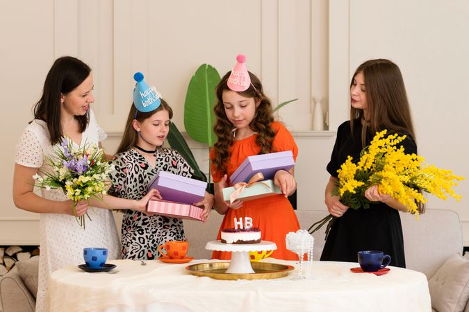 Mother and daughters opening presents at birthday party
