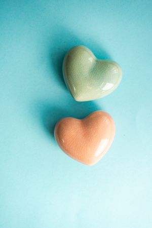 Two ceramic heart ornaments on pastel blue background