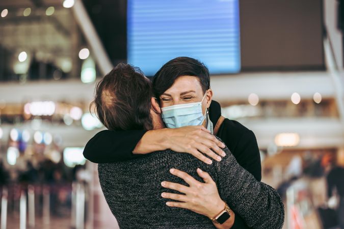 Husband and wife embracing at airport during pandemic