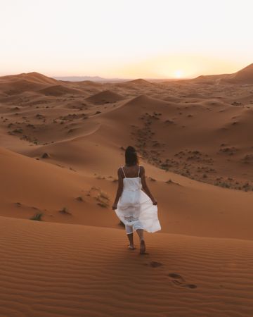Woman in white dress walking in desert