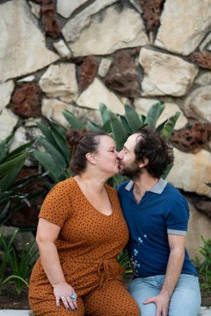 Romantic husband and wife kissing outside in front of stone wall