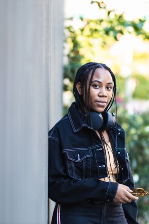 Black woman leaning on wall near park