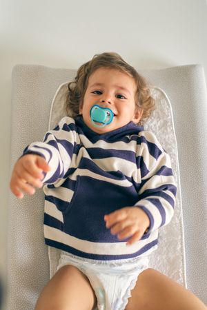 Adorable toddler having fun while lying on changing table
