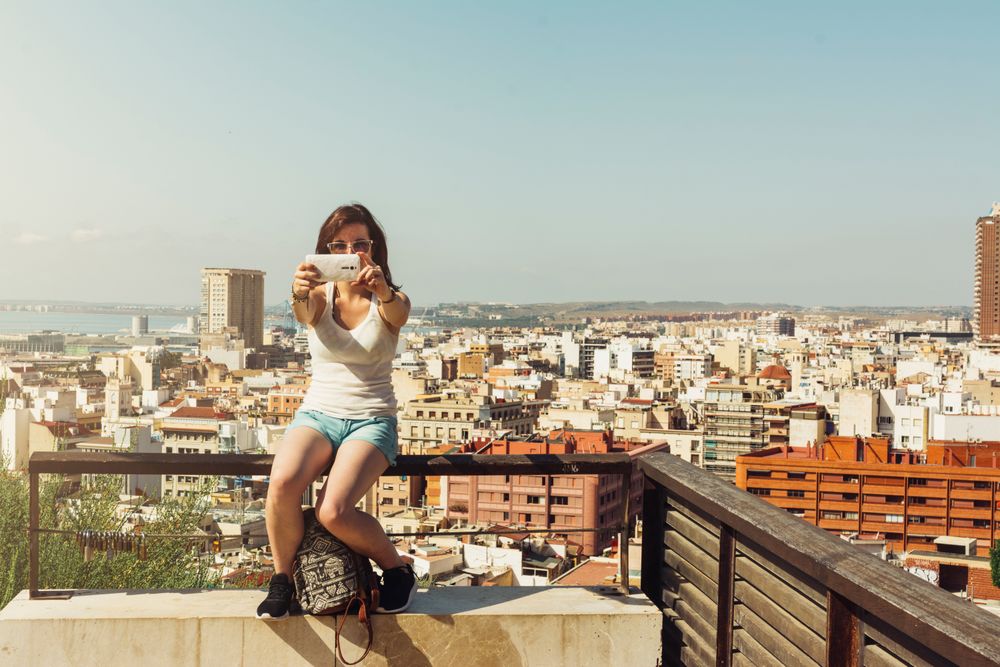 Woman on balcony taking pictures city views from above