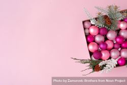 Box of pink festival baubles and branches on pink background 4N2Z94