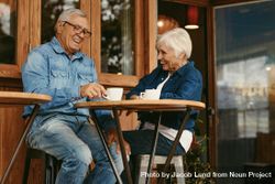 Older couple having conversation while drinking coffee together in cafe 4BgPBb