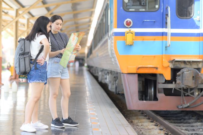 Two young women looking at a map to travel by train