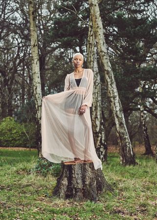 Woman standing on tree stump in mesh dress