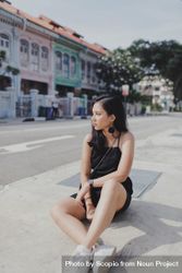 Woman in dark dress sitting on the street 4MJekb