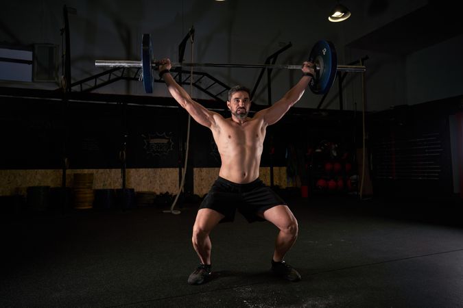 Man with raised hands with barbell while doing weightlifting exe