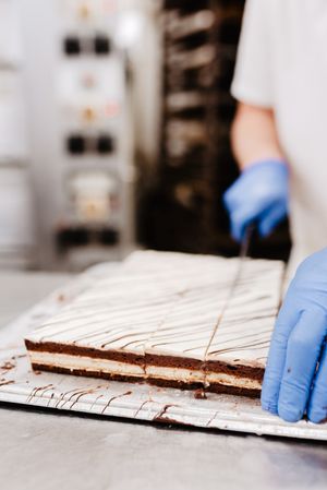 Anonymous cook cutting cake on table
