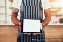 Close up shot of a man wearing an apron showing a digital tablet 5RVOO5
