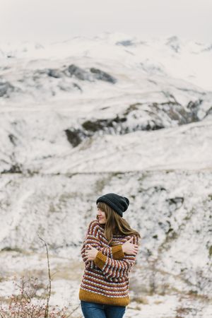 Young woman with crossed hands near mountain