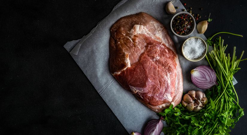 Top view of raw pork steak with herbs, garlic, onion, salt and pepper with copy space