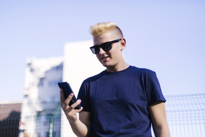Young blond man using a cell phone on the street