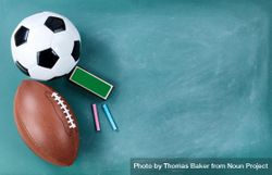 American football and soccer ball on cleaned chalkboard with writing materials bxo1n4