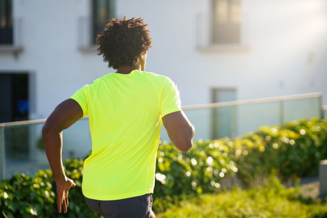 Back of Black man exercising outside in neon shirt