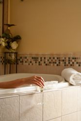 Woman Relaxing in the Bathroom Spa Tub with a Glass of Sparkling Champagne and Candles.