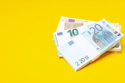 Many bundles of euros on a yellow background.