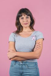 Serious woman wearing pink breast cancer awareness ribbon. Vertical shot.