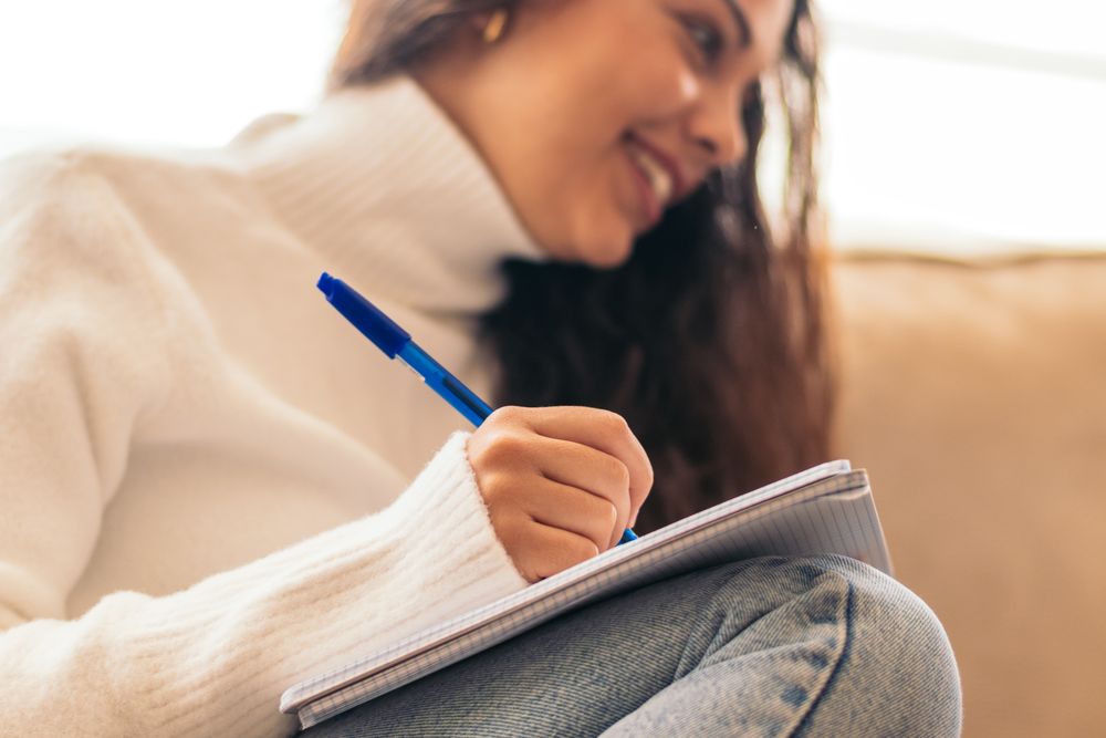 University student studying at home with laptop and notebook