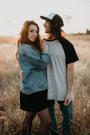 Hipster couple bonding on field in sunlight