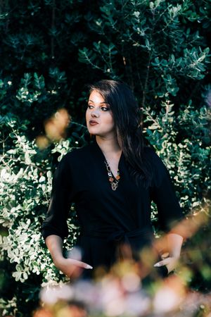 Smiling female looking out of green bushes