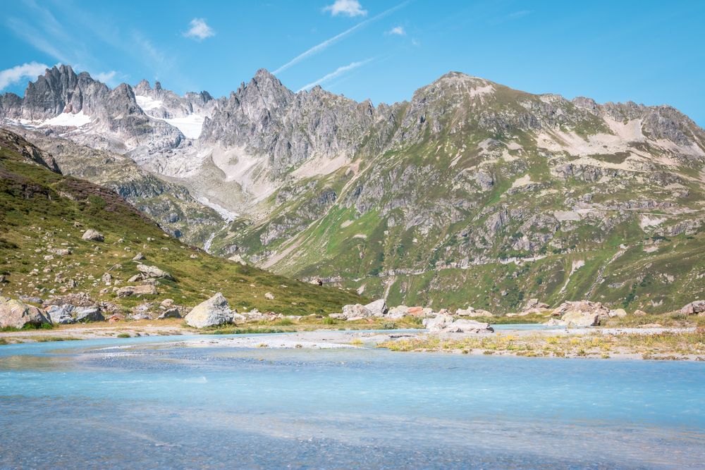Azure water and mountains covered with greens under bright blue sky