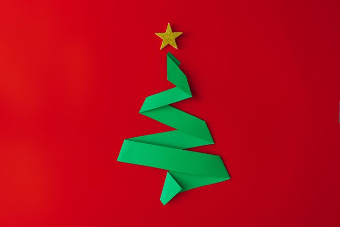Minimal origami style folded paper Christmas tree on red background