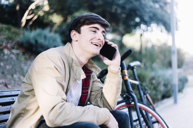Smiling man using mobile phone while sitting outdoors