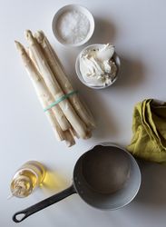 Saucepan and napkin near asparagus and condiments