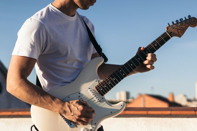 man playing electric guitar on a rooftop