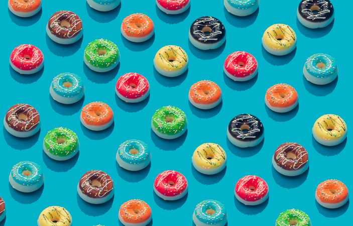 Patten of rows of colorful donuts on blue background