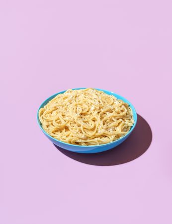 Spaghetti cacio e pepe in a bowl on a purple background