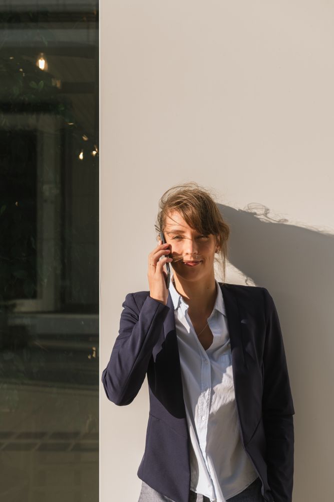 Cheerful female manager speaking on smartphone on street