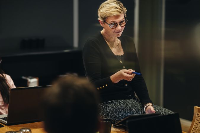 Mature woman sitting on conference table with pen and tablet