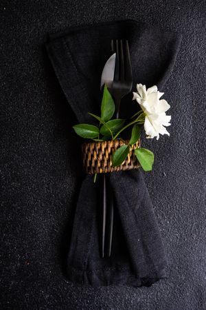 Minimalistic silverware wrapped in napkin with rose