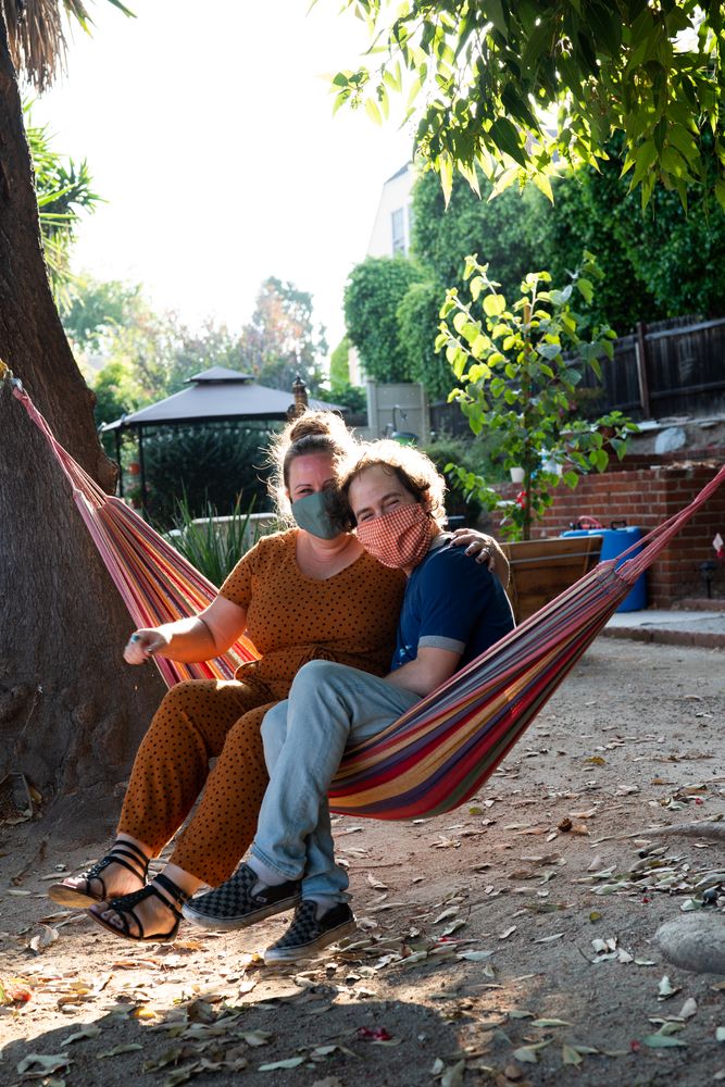 Young couple in a hammock smiling at camera in masks