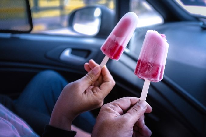 Two people’s hands holding ice pops