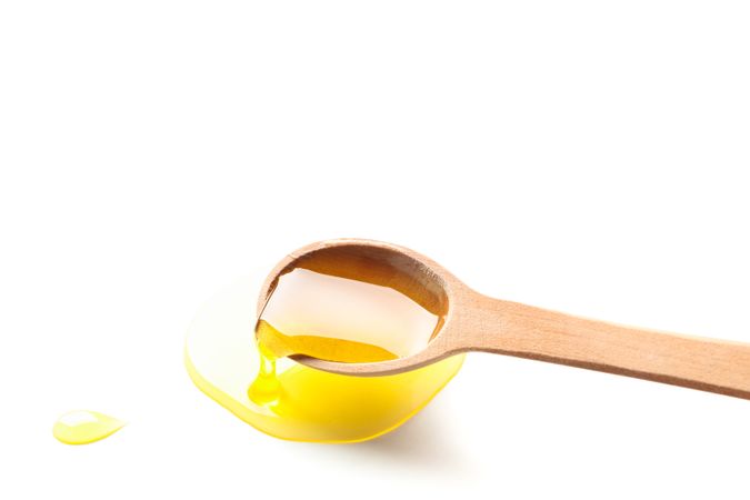 Wooden spoon with honey isolated on plain background, closeup