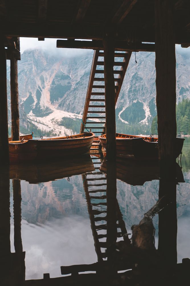 Moored wooden boats at pier on lake in mountains
